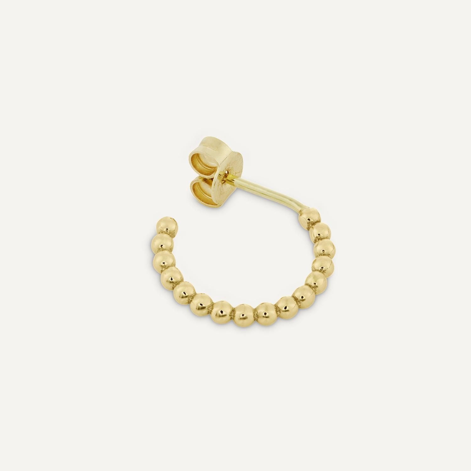 Sicht von oben auf einen Ohrstecker aus kleinen, goldenen Kugeln;