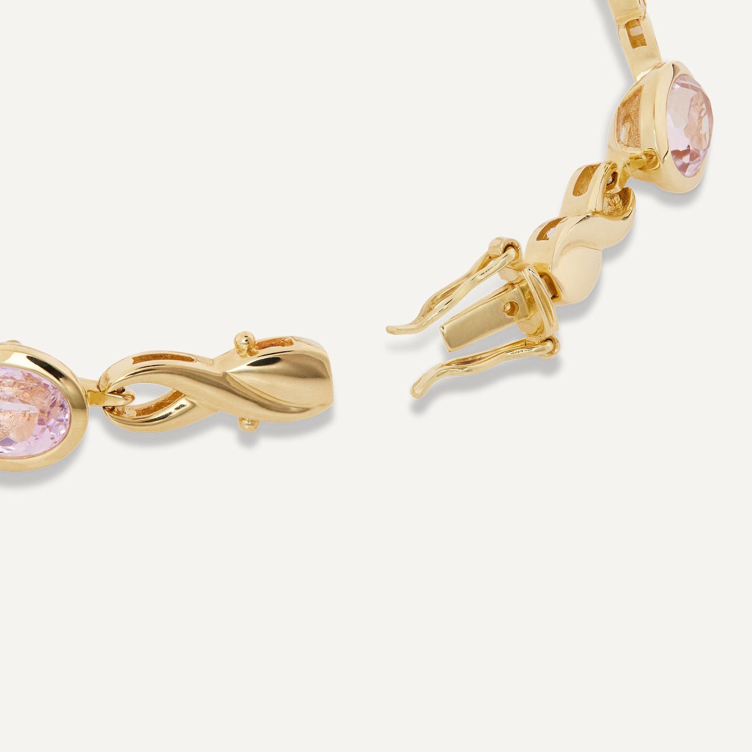 Ausschnitt des Kastenverschlusses an einem goldenen Armband mit eingefassten, helllila, ovalen Steinen; die Verbindung zwischen den einzelnen Steinen ähnelt einer liegenden Acht;