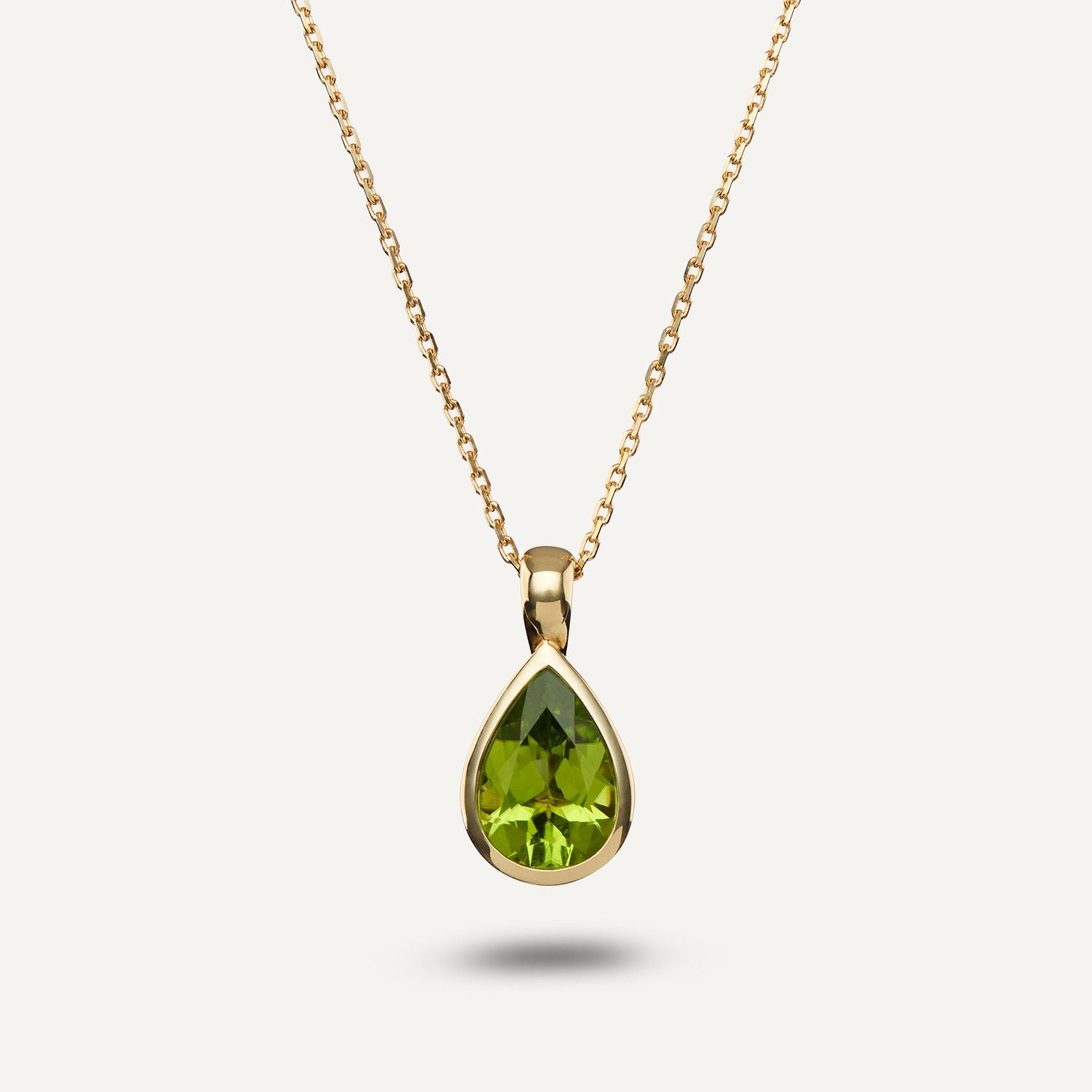 Clip-Anhänger aus Gelbgold mit einem in Gelbgold gefassten, grünen Stein in Tropfenform an einer Gliederkette aus Gelbgold;