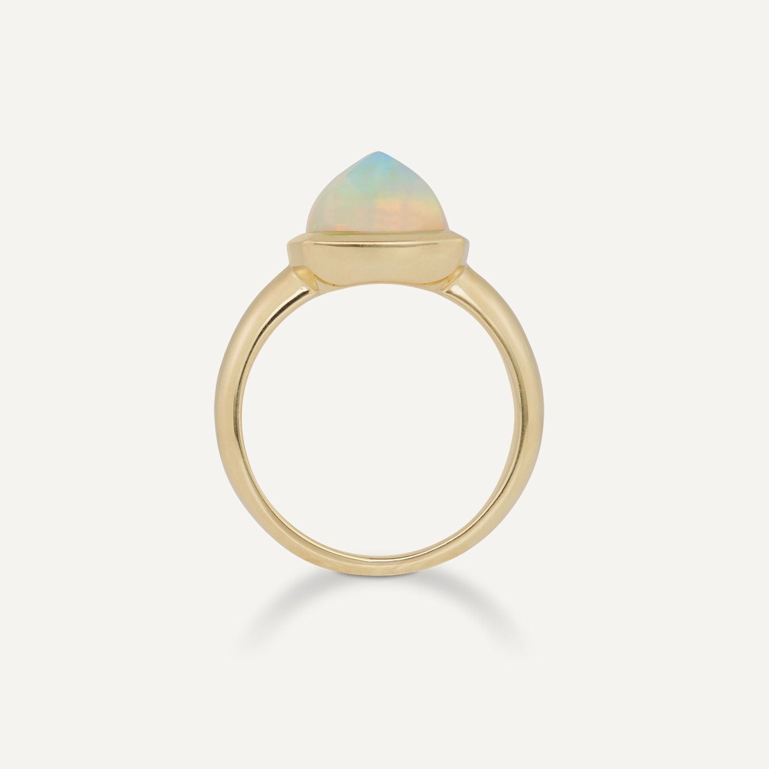 Seitenansicht eines goldenen Rings mit einem großen, gold eingefassten, hell schimmernden Opal; der Opal ragt wie eine Spitze hoch;
