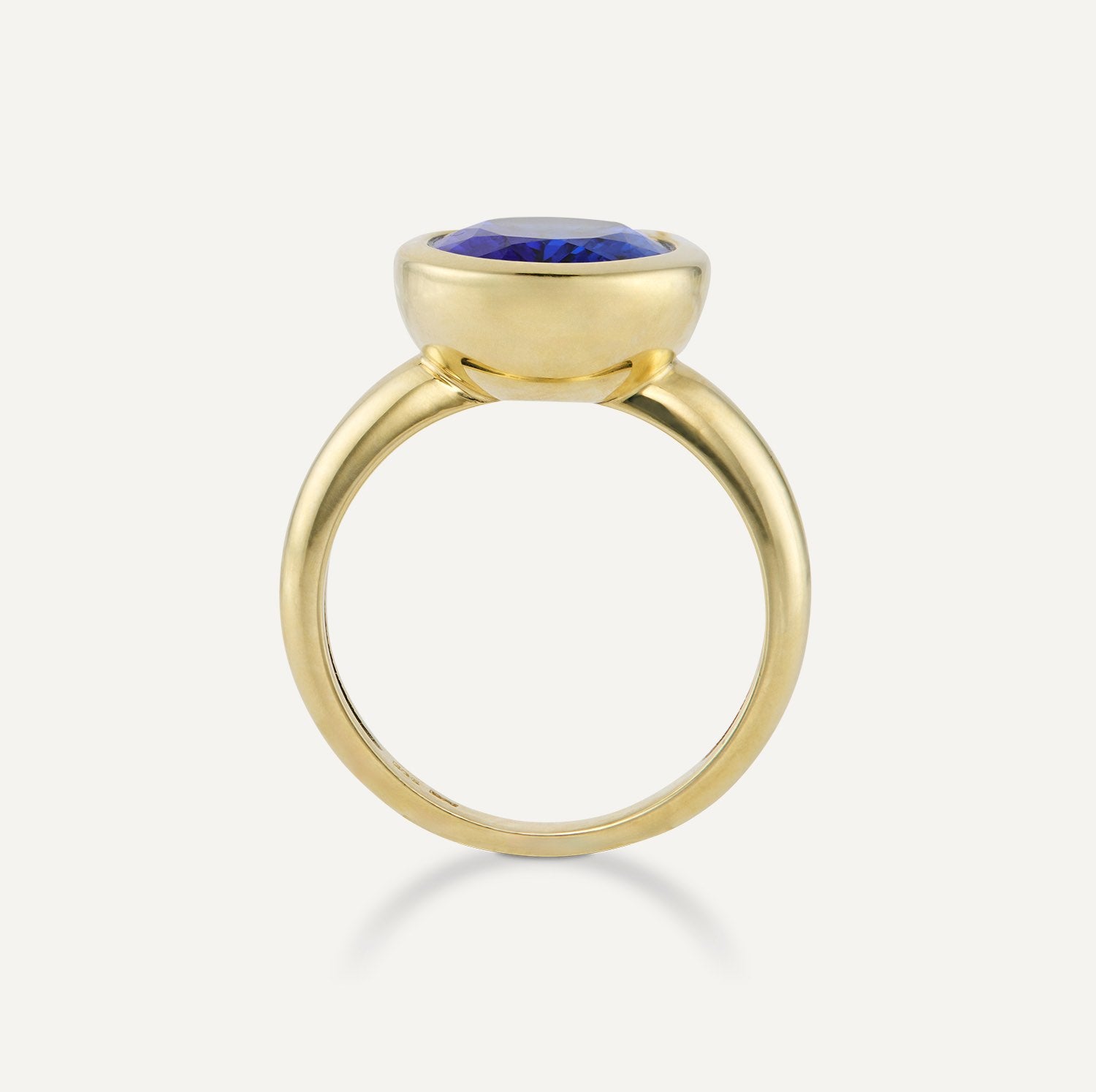 Seitenansicht eines Band-Rings in Gelbgold mit einem in Gelbgold gefassten, runden, blauen Stein;
