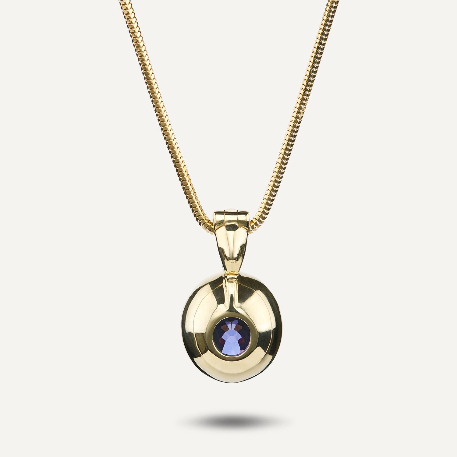 Rückansicht eines Clip-Anhängers in Gelbgold mit einem in Gelbgold gefassten, runden, blauen Stein an einer Schlangenkette aus Gelbgold; die Rückseite des Steins ist fast komplett eingefasst;