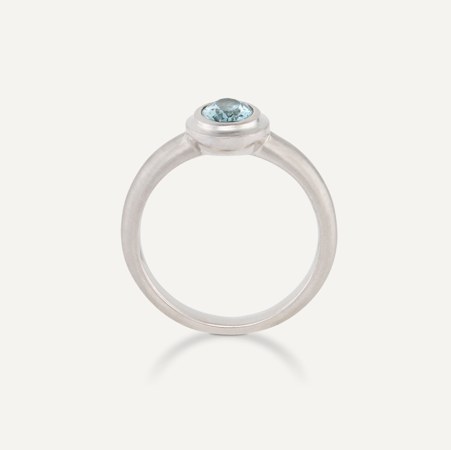 Seitenansicht eines Platin-Rings mit einem in Platin gefassten, ovalen, hellblauen Stein;