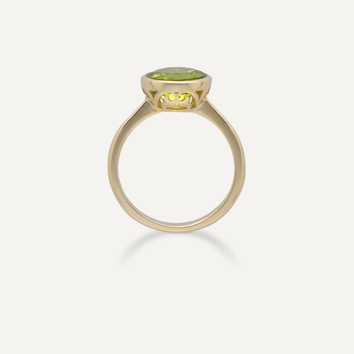 Seitenansicht eines Cocktail-Rings in Gelbgold mit einem in Gelbgold gefassten, runden, grünen Stein;