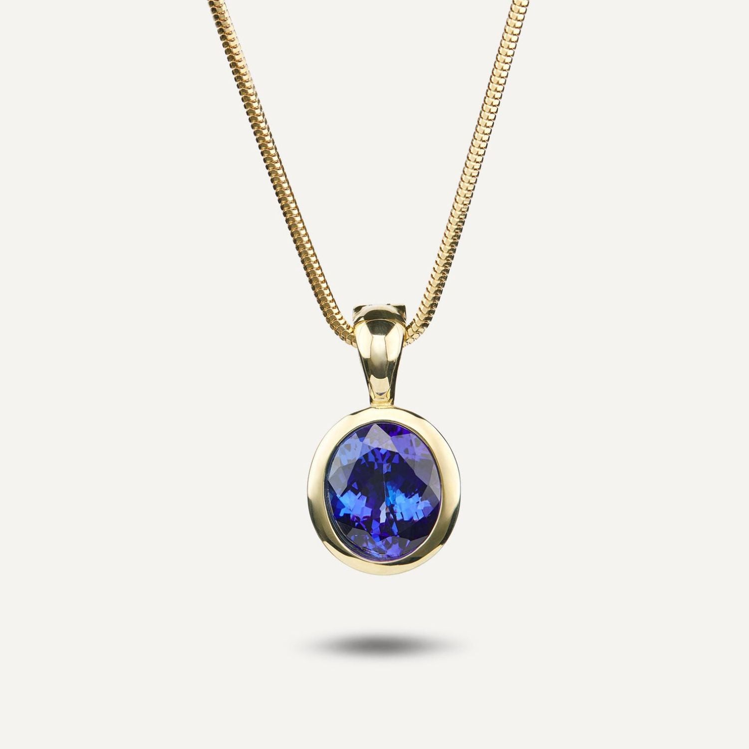 Clip-Anhänger in Gelbgold mit einem in Gelbgold gefassten, runden, blauen Stein an einer Schlangenkette aus Gelbgold;