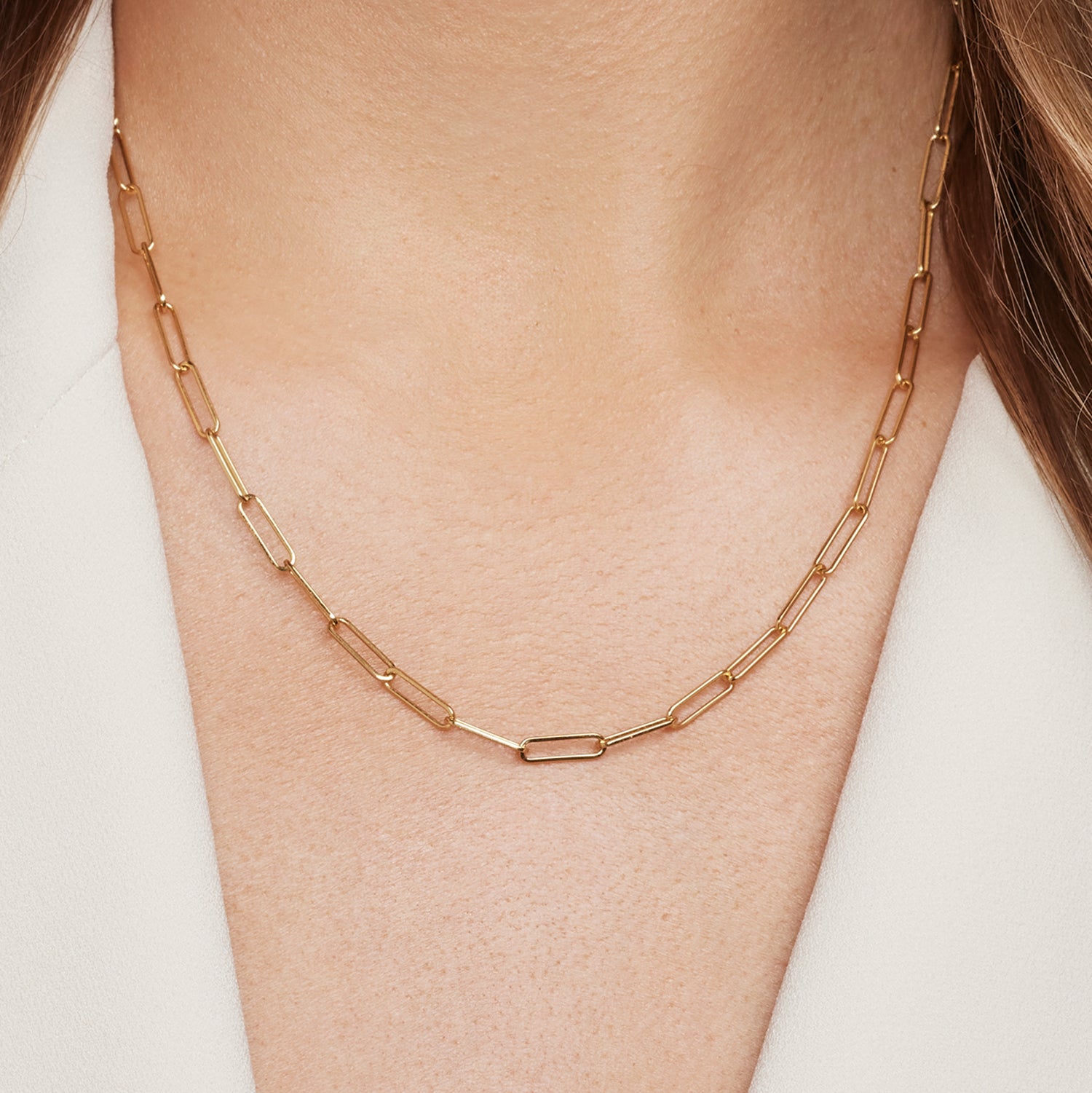 Halsausschnitt einer Frau; sie trägt eine goldene Gliederkette mit großen, feinen Gliedern;