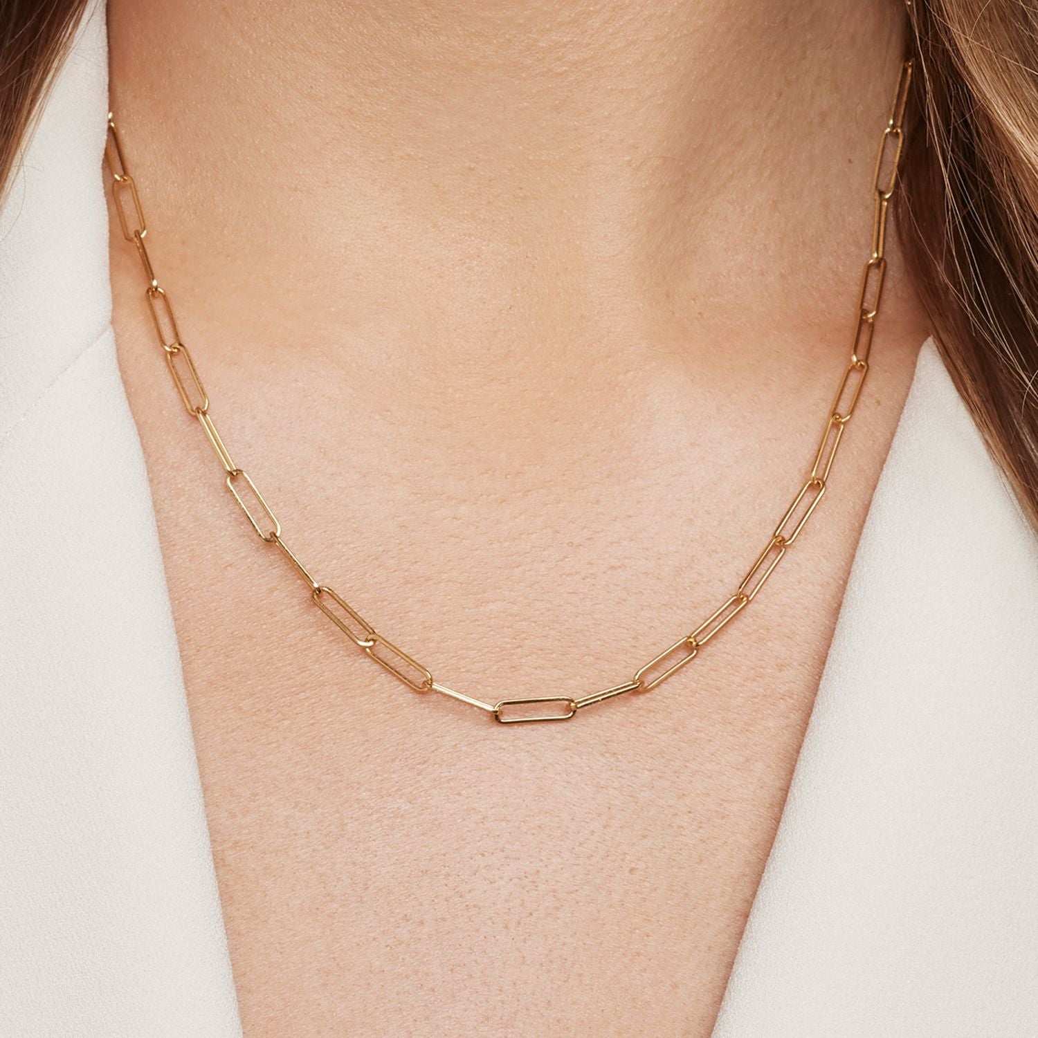 Halsausschnitt einer Frau; sie trägt eine goldene Gliederkette mit großen, feinen Gliedern;