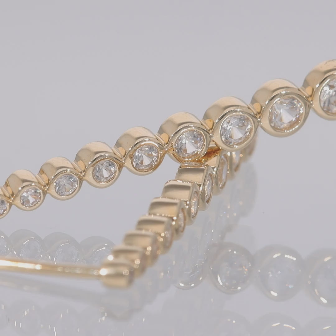 Das Video zeigt zwei aufeinander liegende Ohrstecker in Gelbgold mit in Gelbgold eingefassten, aneinander hängenden, größer werdenden, runden Zirkonen;