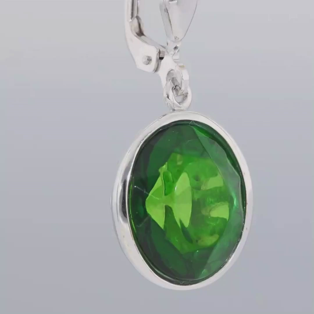 Das Video zeigt einen Ohrhänger in Silber mit einem fast runden, grünen Bernstein in Silber eingefasst;