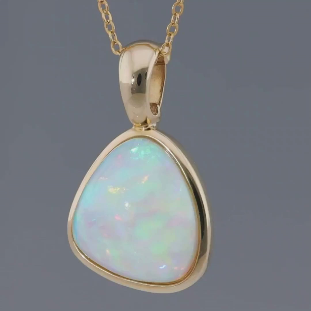 Das Video zeigt einen goldenen kreisbogenförmigen Clip-Anhänger mit einem eingefassten bläulich schimmernden Kristallopal an einer goldenen Gliederkette; der Anhänger dreht sich hin und her;