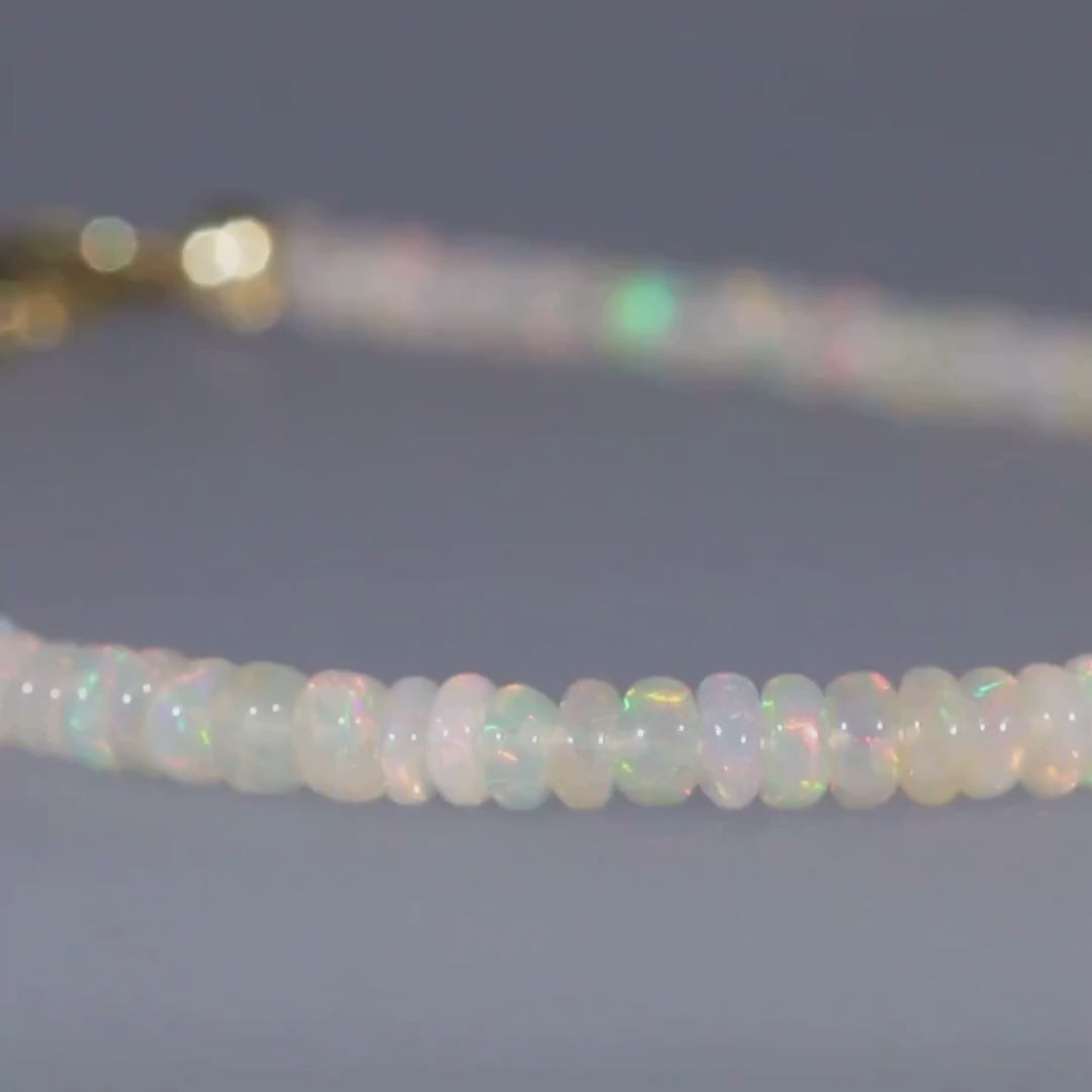 Das Video zeigt ein Armband mit direkt aneinandergereihten hell schimmernden Kristallopalen und einem goldenen Karabinerverschluss; es dreht sich hin und her;