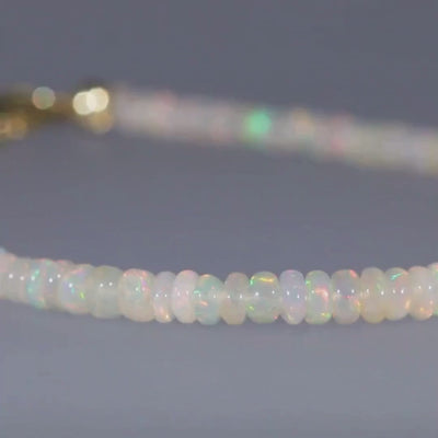 Das Video zeigt ein Armband mit direkt aneinandergereihten hell schimmernden Kristallopalen und einem goldenen Karabinerverschluss; es dreht sich hin und her;