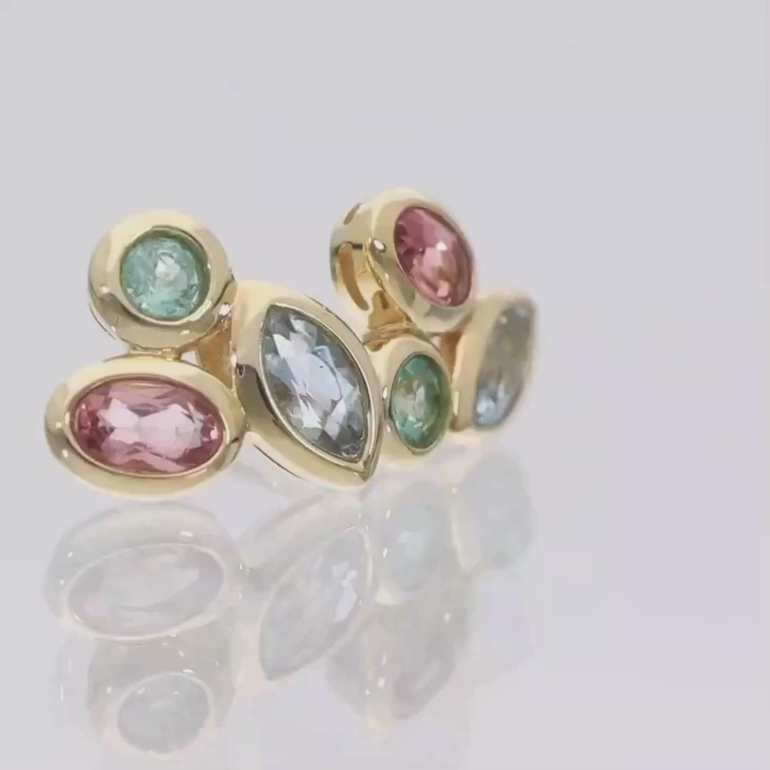 Das Video zeigt zwei Ohrstecker in Gelbgold mit drei aneinander gefassten Steinen in unterschiedlichen Farben und Formen: rot/oval, grün/rund, blau/tropfenförmig; die beiden Ohrstecker liegen auf einer spiegelnden Oberfläche;